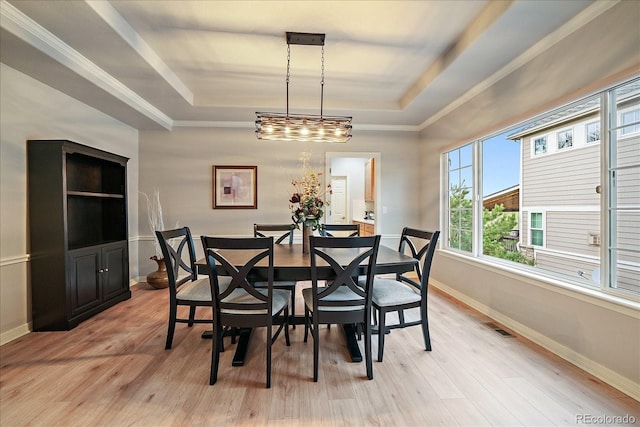 dining room featuring a tray ceiling, baseboards, and light wood-style floors