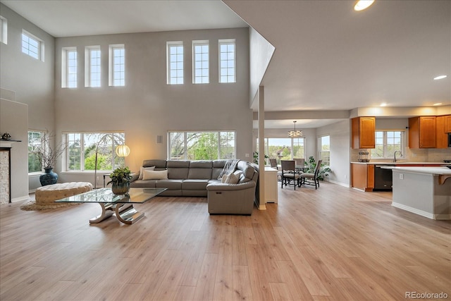 living room with light wood-style flooring, plenty of natural light, recessed lighting, and a high ceiling
