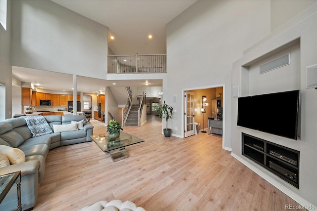 living area featuring light wood-style flooring, stairs, a high ceiling, and recessed lighting