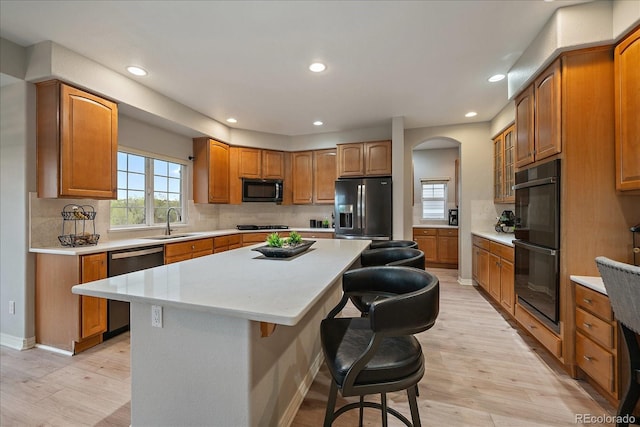 kitchen featuring black appliances, a kitchen breakfast bar, a sink, a center island, and recessed lighting