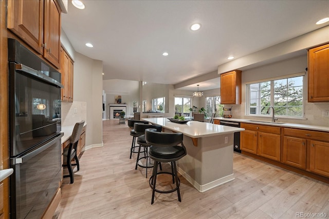 kitchen featuring dishwashing machine, a sink, a center island, decorative backsplash, and light countertops