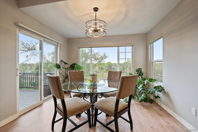 dining area featuring healthy amount of natural light, baseboards, a chandelier, and light wood finished floors