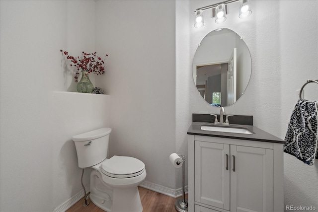 bathroom featuring baseboards, wood finished floors, vanity, and toilet