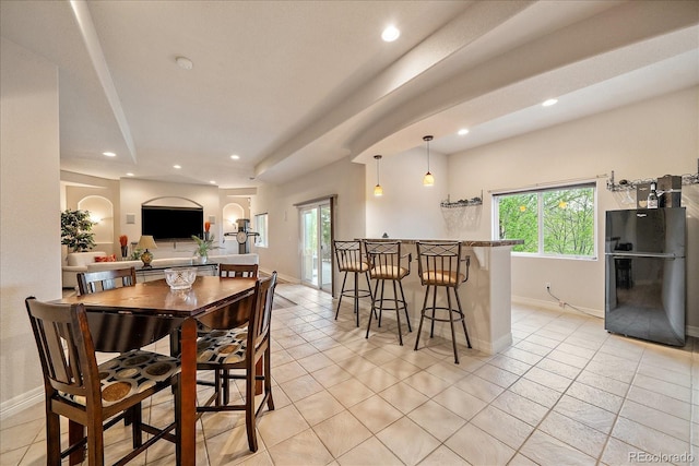 dining room featuring recessed lighting, baseboards, a bar, light tile patterned floors, and arched walkways