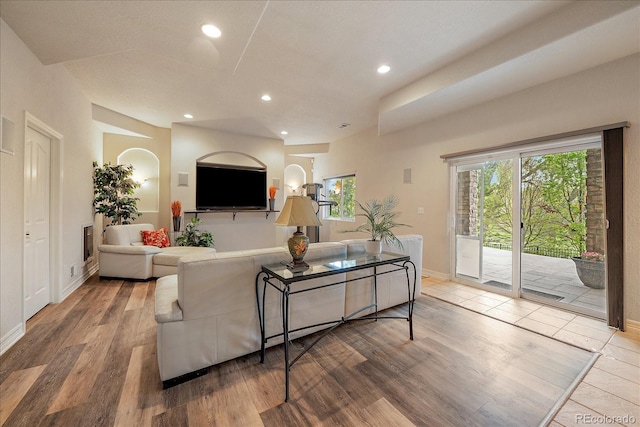 living area featuring wood finished floors, recessed lighting, baseboards, and arched walkways