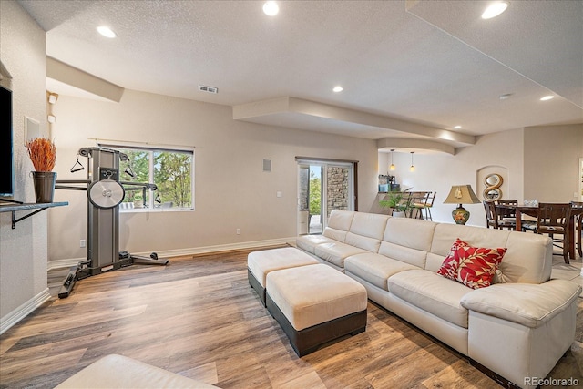 living area featuring recessed lighting, wood finished floors, baseboards, and a textured ceiling