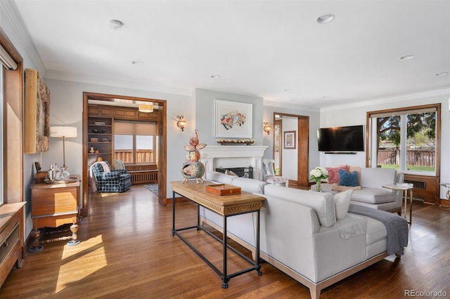 living area featuring a fireplace, ornamental molding, a healthy amount of sunlight, and dark wood finished floors