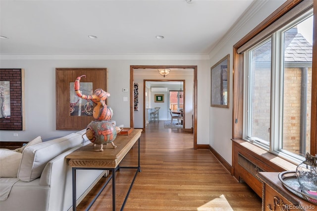 corridor featuring baseboards, ornamental molding, a healthy amount of sunlight, and light wood-style flooring