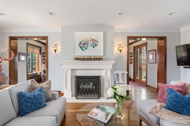 living room featuring baseboards, ornamental molding, a fireplace with raised hearth, and wood finished floors