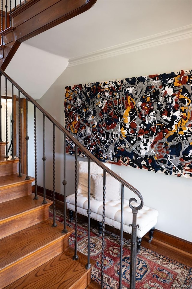 staircase featuring baseboards, ornamental molding, and wood finished floors