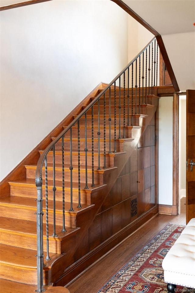 stairs featuring a towering ceiling and wood finished floors