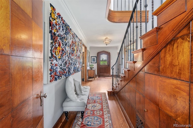 foyer with baseboards, ornamental molding, wood finished floors, arched walkways, and stairway