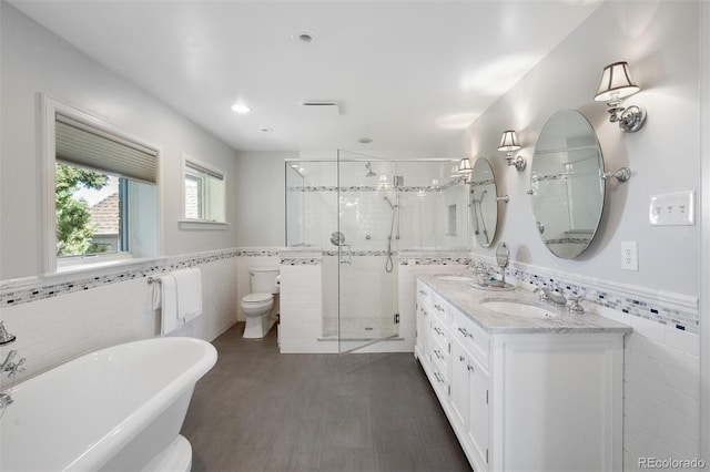 full bath with a stall shower, a sink, a soaking tub, tile walls, and wainscoting