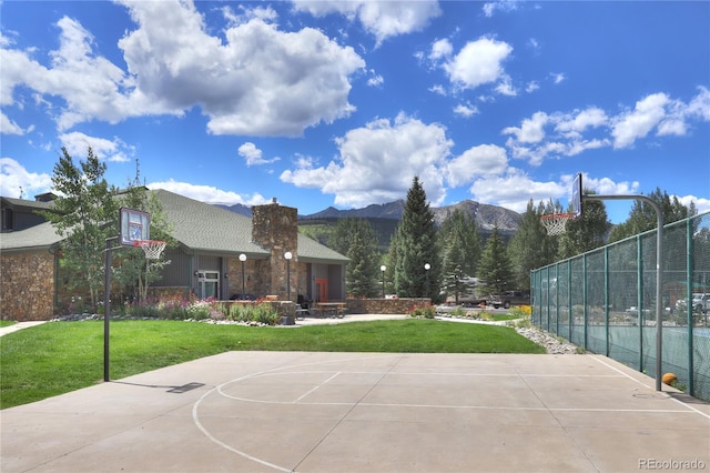 view of basketball court featuring a lawn and a mountain view