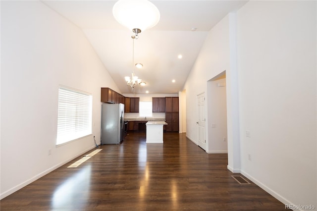 kitchen with stainless steel fridge, pendant lighting, high vaulted ceiling, a center island, and dark hardwood / wood-style floors