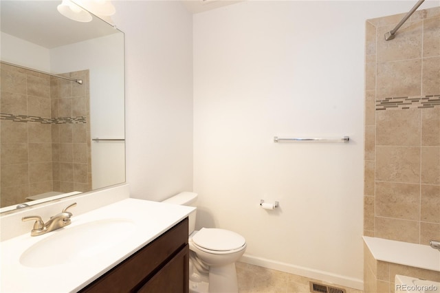 bathroom featuring tile patterned flooring, vanity, toilet, and tiled shower