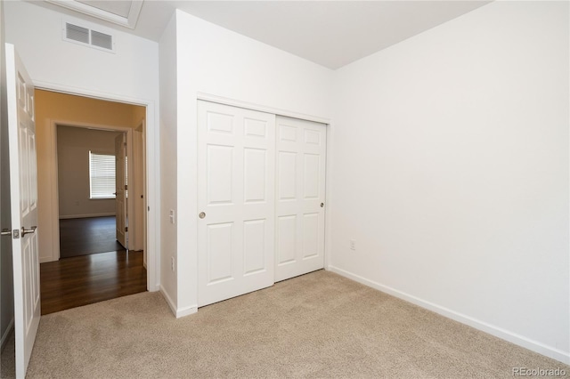 unfurnished bedroom with light colored carpet and a closet