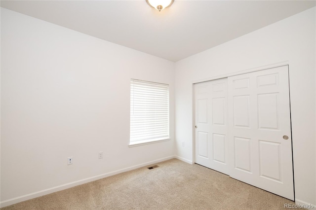 unfurnished bedroom with light carpet and a closet