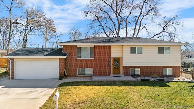 raised ranch featuring brick siding, fence, a front yard, driveway, and an attached garage