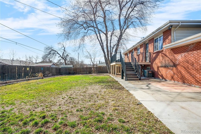 view of yard featuring a wooden deck, central air condition unit, a fenced backyard, and stairs