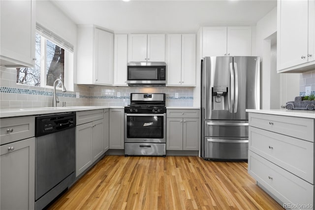 kitchen featuring appliances with stainless steel finishes, light wood-type flooring, light countertops, and gray cabinetry