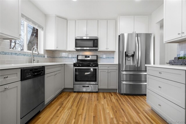 kitchen with light countertops, light wood-style floors, gray cabinets, and appliances with stainless steel finishes