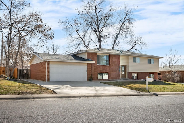 raised ranch featuring fence, driveway, an attached garage, a front lawn, and brick siding