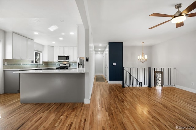 kitchen featuring tasteful backsplash, light wood-type flooring, light countertops, white cabinets, and stainless steel appliances