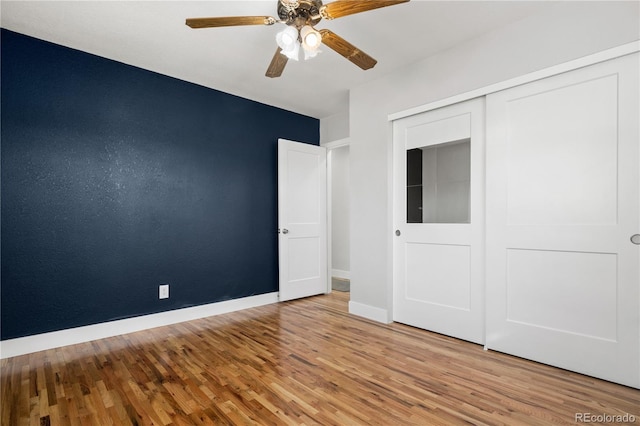 unfurnished bedroom featuring ceiling fan, a closet, baseboards, and wood finished floors