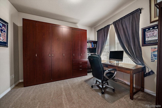 carpeted office space featuring a textured ceiling and baseboards