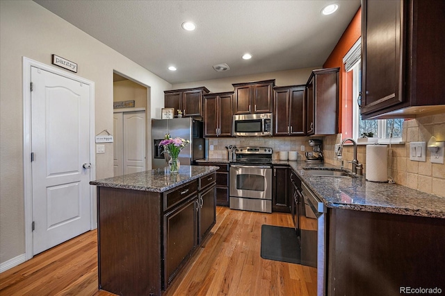 kitchen featuring dark brown cabinetry, appliances with stainless steel finishes, light wood finished floors, and a sink