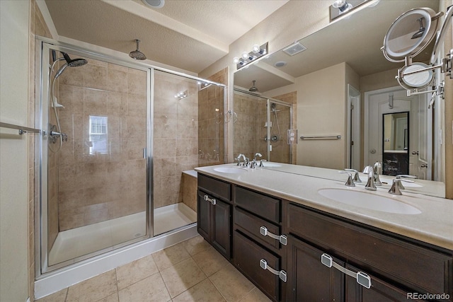 bathroom featuring tile patterned flooring, a sink, visible vents, double vanity, and a stall shower