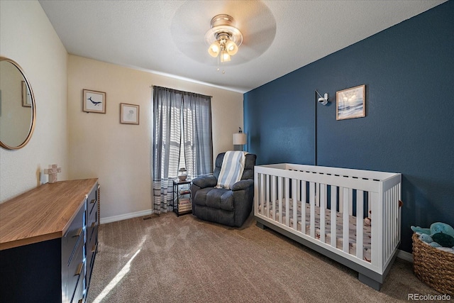 bedroom with baseboards, ceiling fan, a textured ceiling, carpet flooring, and a nursery area