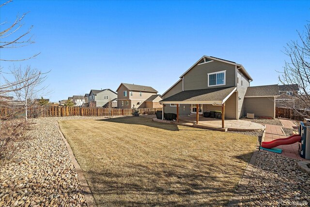 back of house featuring a playground, a lawn, a patio area, a residential view, and a fenced backyard