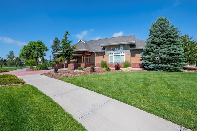 prairie-style home with brick siding and a front yard