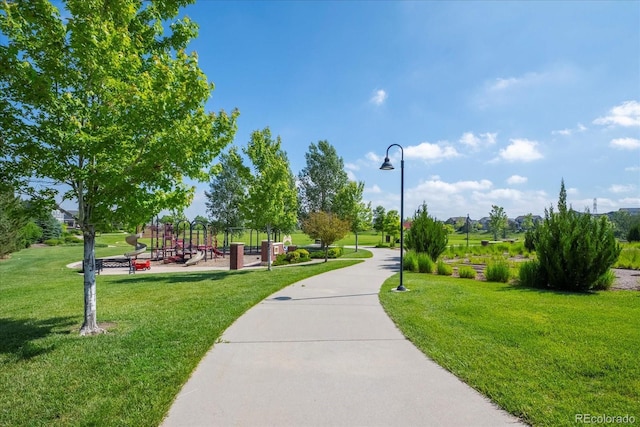 view of home's community with playground community and a lawn