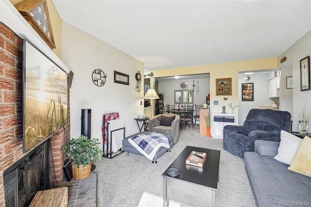 carpeted living area featuring a brick fireplace and a textured ceiling