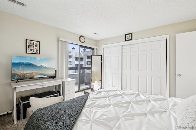 bedroom featuring visible vents, a textured ceiling, carpet floors, and a closet