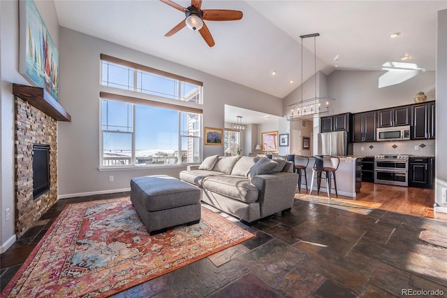 living room with ceiling fan, a fireplace, and high vaulted ceiling