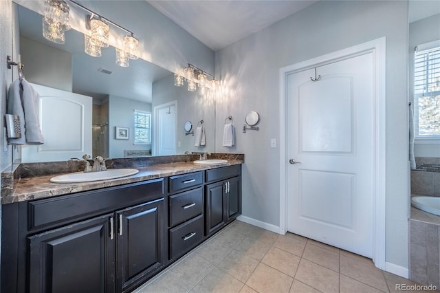 bathroom with tile patterned flooring, vanity, a chandelier, and a tub