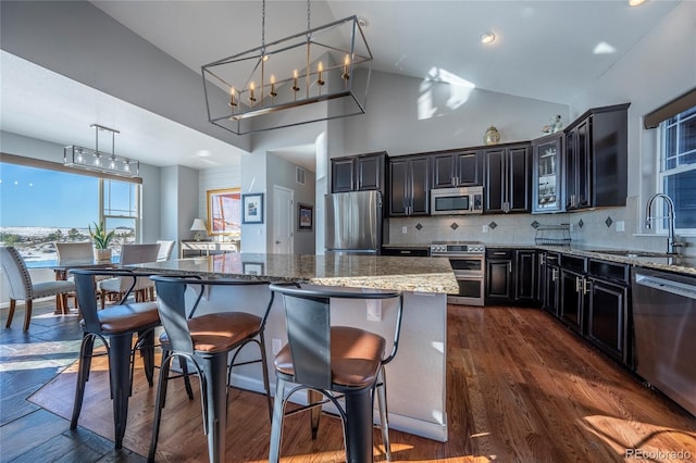 kitchen featuring sink, tasteful backsplash, dark stone counters, a kitchen island, and appliances with stainless steel finishes