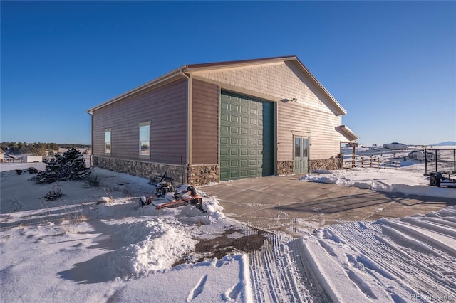 view of snowy exterior with a garage and an outdoor structure