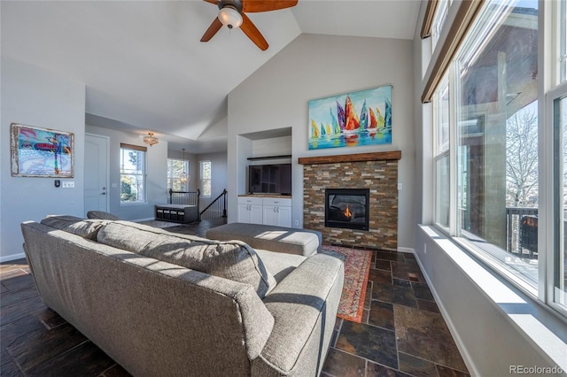 living room featuring a stone fireplace, ceiling fan, and vaulted ceiling