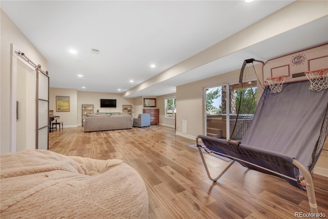 living room with a barn door and light hardwood / wood-style floors