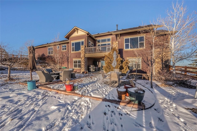 snow covered rear of property with a balcony and a patio