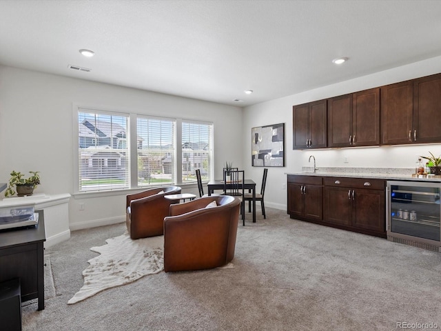 10258 W Coal Mine Pl, Littleton, CO 80127 - living area featuring beverage cooler, light carpet, bar with sink, baseboards, and recessed lighting
