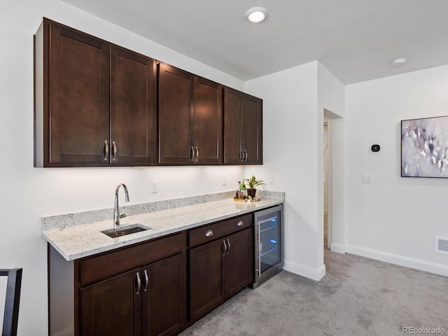 10258 W Coal Mine Pl, Littleton, CO 80127 - kitchen with beverage cooler, a sink, light carpet, dark brown cabinetry, and light stone counters