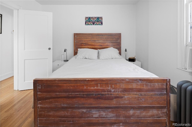 bedroom with light hardwood / wood-style flooring and radiator heating unit