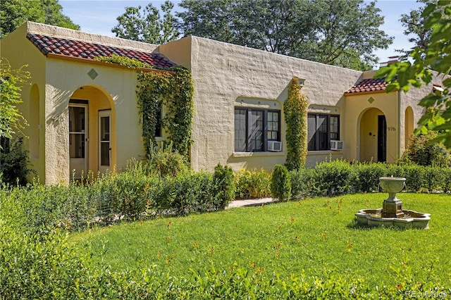 mediterranean / spanish house featuring cooling unit and a front yard