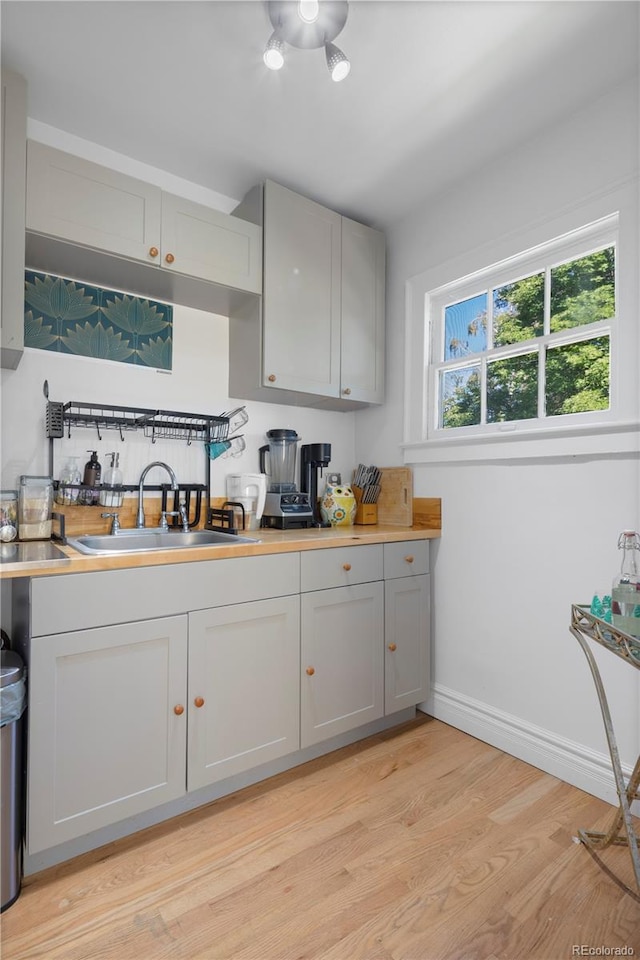 kitchen with gray cabinetry, light hardwood / wood-style flooring, and sink